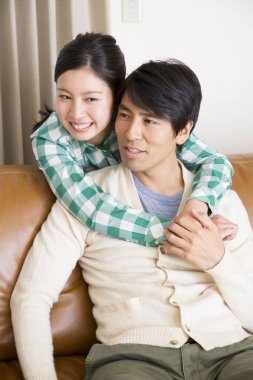 Genç Asyalı kadın ve erkek evde dinleniyor.