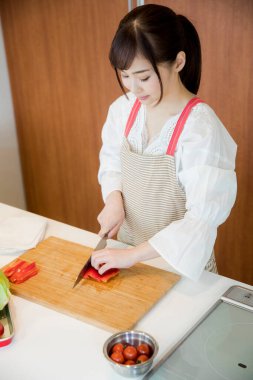 Güzel Asyalı kadın mutfakta biber kesiyor.