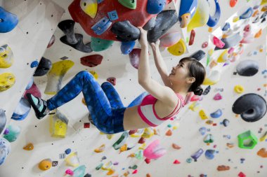 Güzel Japon kadın spor salonunda duvara tırmanıyor. 