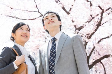 Şehir caddesinde kiraz çiçekleri olan iki Japon iş adamı.