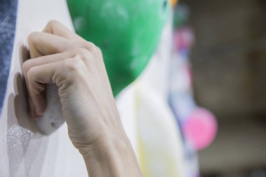 Kayalık spor salonunda yapay tırmanma duvarına tırmanan bir adam.