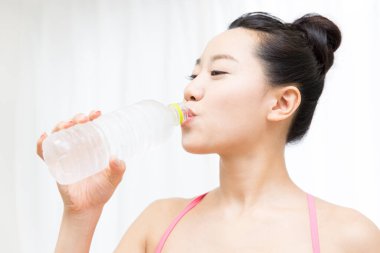 young asian woman drinking water in fitness gym