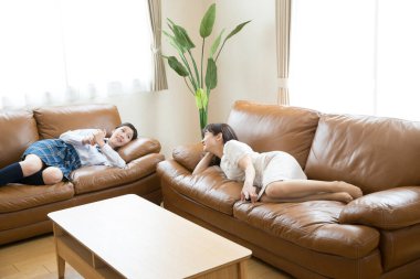 two asian women on sofas at home
