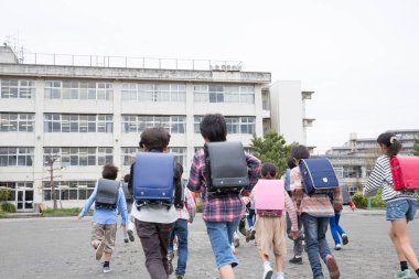 Asyalı bir grup öğrenci okulda yürüyor. 