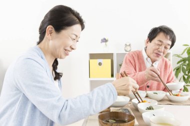 Üst düzey Asyalı çift mutfakta yemek yiyor.