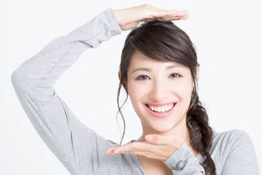 Asyalı genç bir kadın elleriyle çerçevesini gösteriyor.