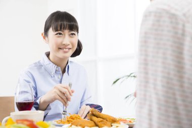 Asyalı kadın mutfakta yemek yiyor. 