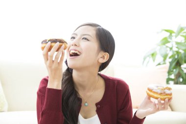 Genç Asyalı kadın donut yiyor.