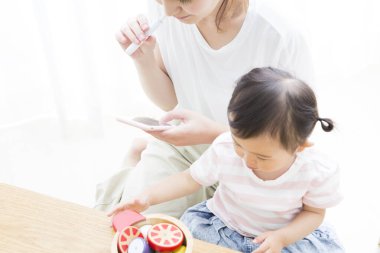 Çocuk oynarken akıllı telefon kullanan kadın