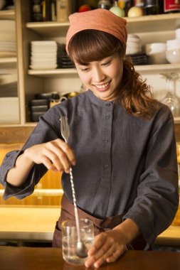 Genç Asyalı garson kız restoranda kokteyl yapıyor. 