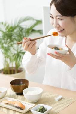 Genç Japon kadın çubuklarla yemek yiyor.