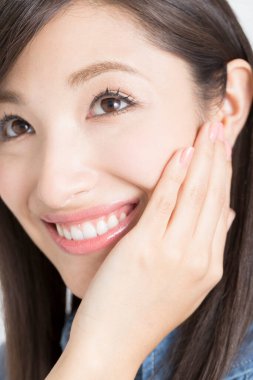 Genç Asyalı kadın elleriyle yüzüne dokunuyor.