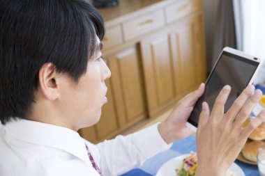 İş adamı dijital tabletle kahvaltı yapıyor