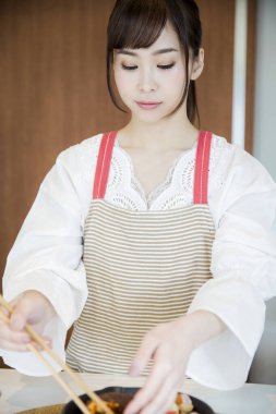 Güzel Asyalı kadın mutfakta yemek yapıyor.