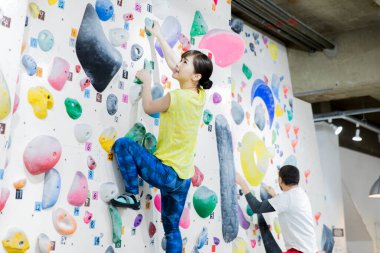 Spor salonundaki Asyalı gençler duvara tırmanıyor. 