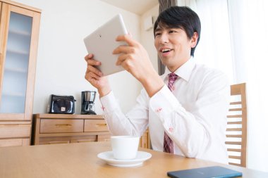 İş adamı masasında tablet tutuyor. 