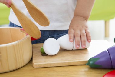 Çocuk ahşap mutfak oyuncaklarıyla oynuyor