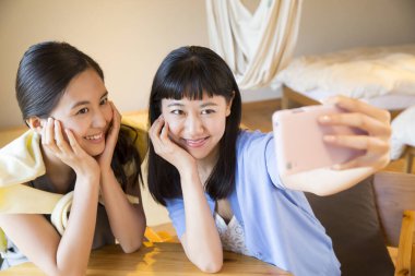 Asyalı genç kadınlar cep telefonlarıyla selfie çekiyorlar..