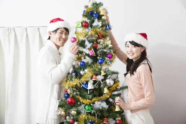 Ευτυχισμένο Νεαρό Ασιατικό Ζευγάρι Στολίζει Χριστουγεννιάτικο Δέντρο — Φωτογραφία Αρχείου