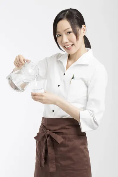Vrolijk Aziatische Serveerster Gieten Water Van Kruik Glas — Stockfoto