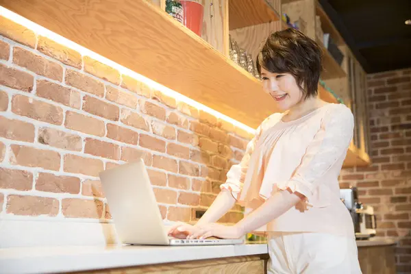 在咖啡店的笔记本电脑上工作的年轻亚洲女人 — 图库照片