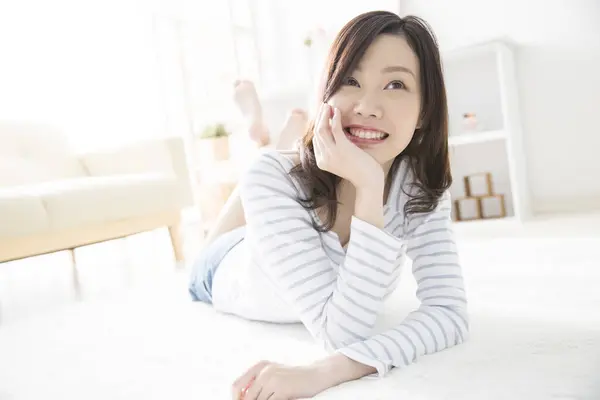 Kaunis Aasialainen Nainen Makaa Lattialla Olohuoneessa — kuvapankkivalokuva