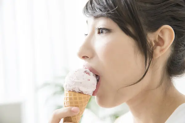 asian woman eating ice cream cone at home