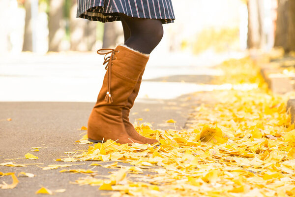 Девушка с желтыми листьями клена в осеннем парке.
