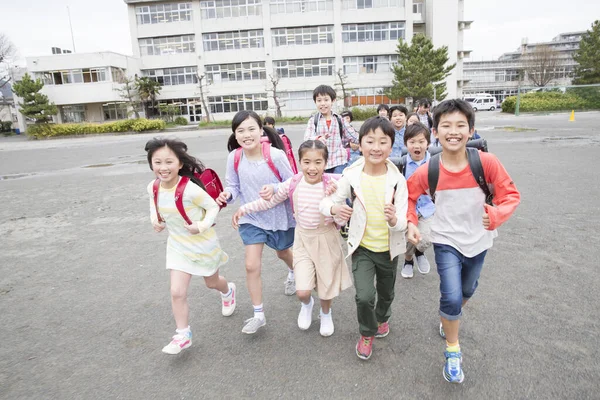 Grupa Japońskich Dzieci Plecakami Biegającymi Szkolnym Podwórku — Zdjęcie stockowe