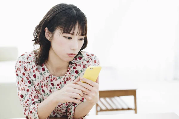 漂亮的年轻亚洲女人在家里用智能手机 — 图库照片