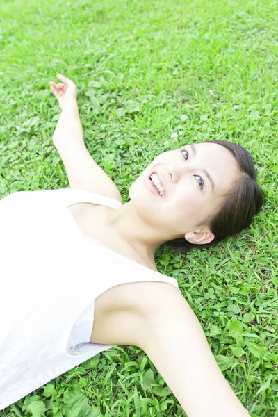 夏の公園の緑の草の上に横たわる白いドレスで美しい日本の女性 — ストック写真