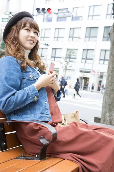 Ung Asiatisk Kvinde Sidder Byen Med Smartphone - Stock-foto