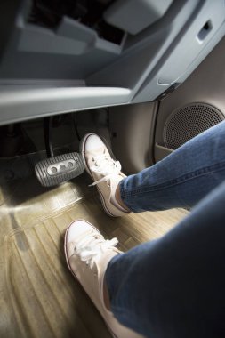 Biri spor ayakkabı giyerek araba fren pedalına basıyor.