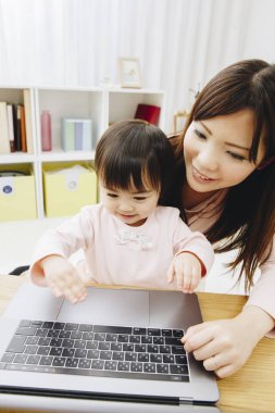 Güzel Asyalı anne ve kızını dizüstü bilgisayarla kapat.