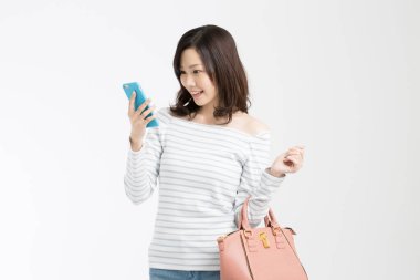 Beyaz arka planda akıllı telefonu olan güzel bir Japon kadının stüdyo fotoğrafı. 