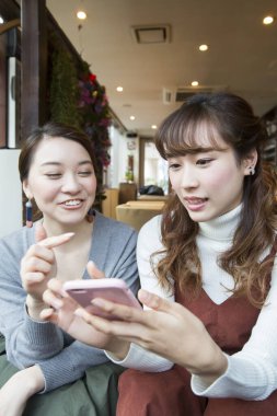 Restoranda telefonu olan Asyalı arkadaşlar.