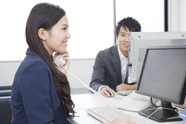 Genç iş kadını ofiste telefonda konuşuyor. 