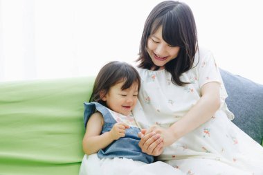 Evdeki oturma odasında annesiyle oynayan tatlı Asyalı küçük kız.