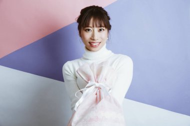 Stüdyo arka planında hediye olan genç, güzel Asyalı kadın.