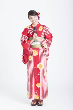 Elinde mikrofon tutan geleneksel Japon kimonosuyla güzel bir genç kadının portresi.