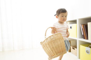 Asyalı bebek hasır sepetle oynuyor.