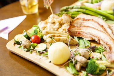 Tabakta çeşit çeşit et ve sebzeler.