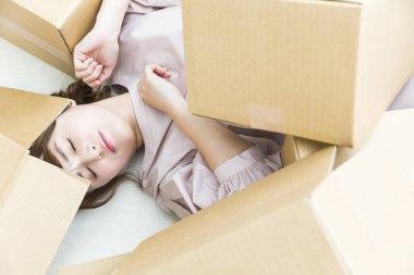 Karton kutularla yerde yatan genç bir kadın. 