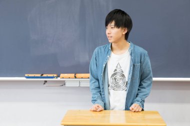 Okuldaki genç Asyalı öğrenci tahtaya yakın.