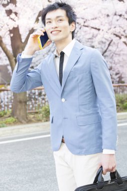 Parkta akıllı telefonu olan yakışıklı bir iş adamı. 