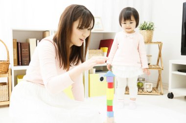 Anne ve kızı bloklarla oynuyorlar. 