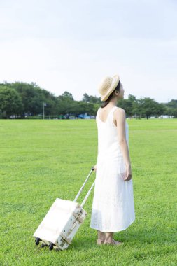 Yaz parkında bavullu bir kadın. 