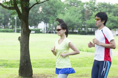 Sportif genç Asyalı çift parkta koşuyor.