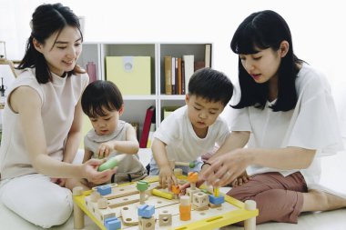 Çocuklarla evde oynayan gülümseyen Asyalı anneler