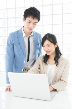 Genç Japon iş adamları ofiste dizüstü bilgisayarla çalışıyorlar.